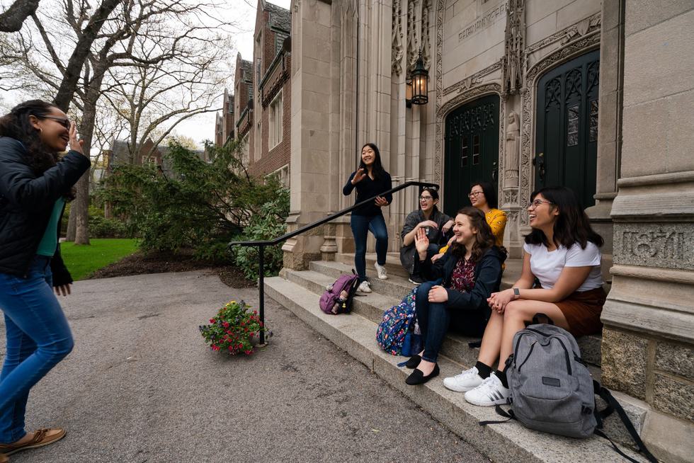 A group of student laugh together while sitting on the steps outside Green Hall.