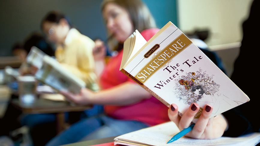Wellesley College student reads a copy of The Winter's tale by Shakespeare in a classroom