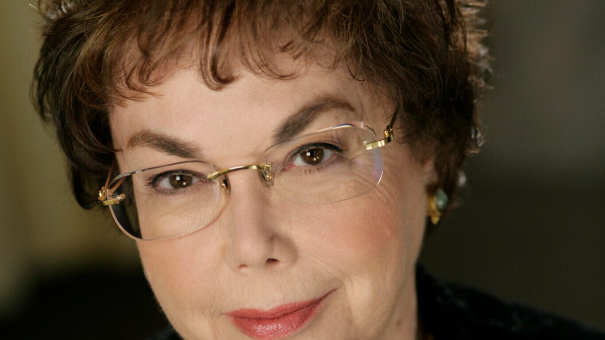 Headshot of Laurie Wilson who has short brown hair, glasses and wears a black sweater with a pendant.