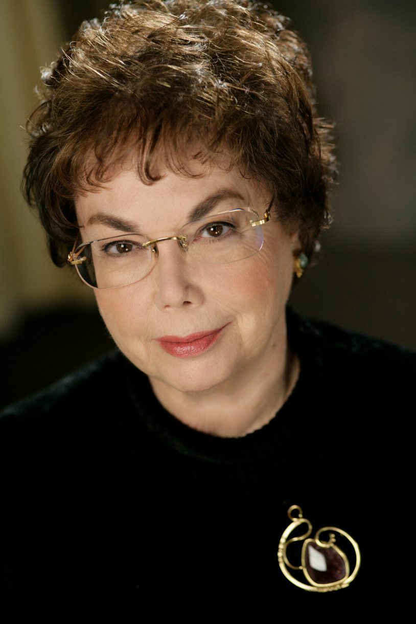 Headshot of Laurie Wilson who has short brown hair, glasses and wears a black sweater with a pendant.