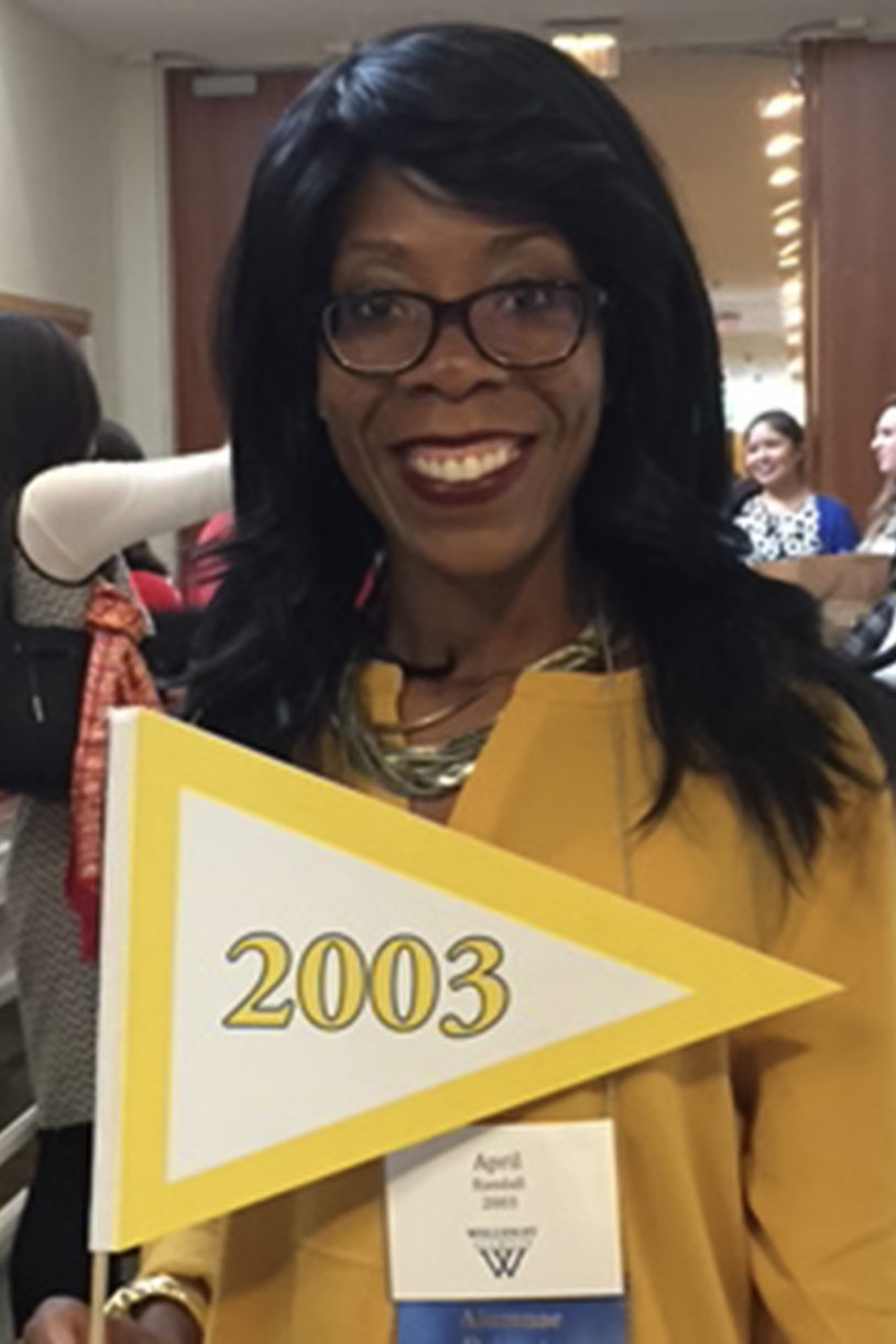 Woman wearing yellow jacket and holding a yellow flag with 2003 written on it.