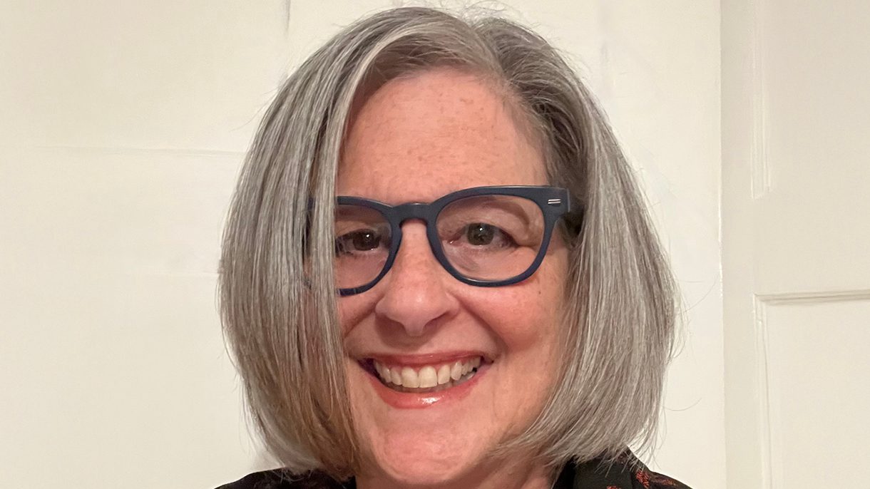 A headshot of a woman with chin length hair and dark-rimmed glasses.