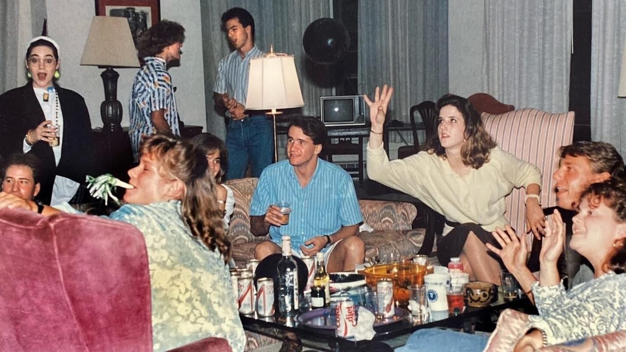 People seating on couches and chairs around a low table full of beverages