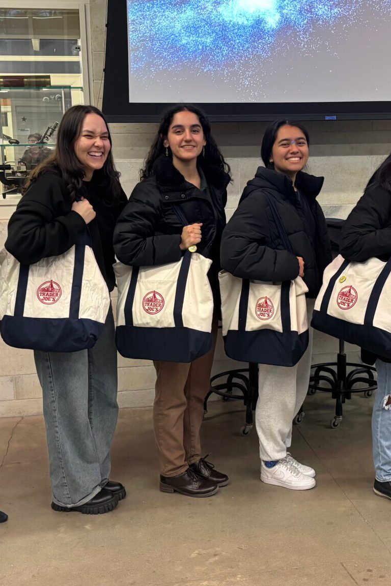 A professor and four students pose with Trader Joe's tote bags