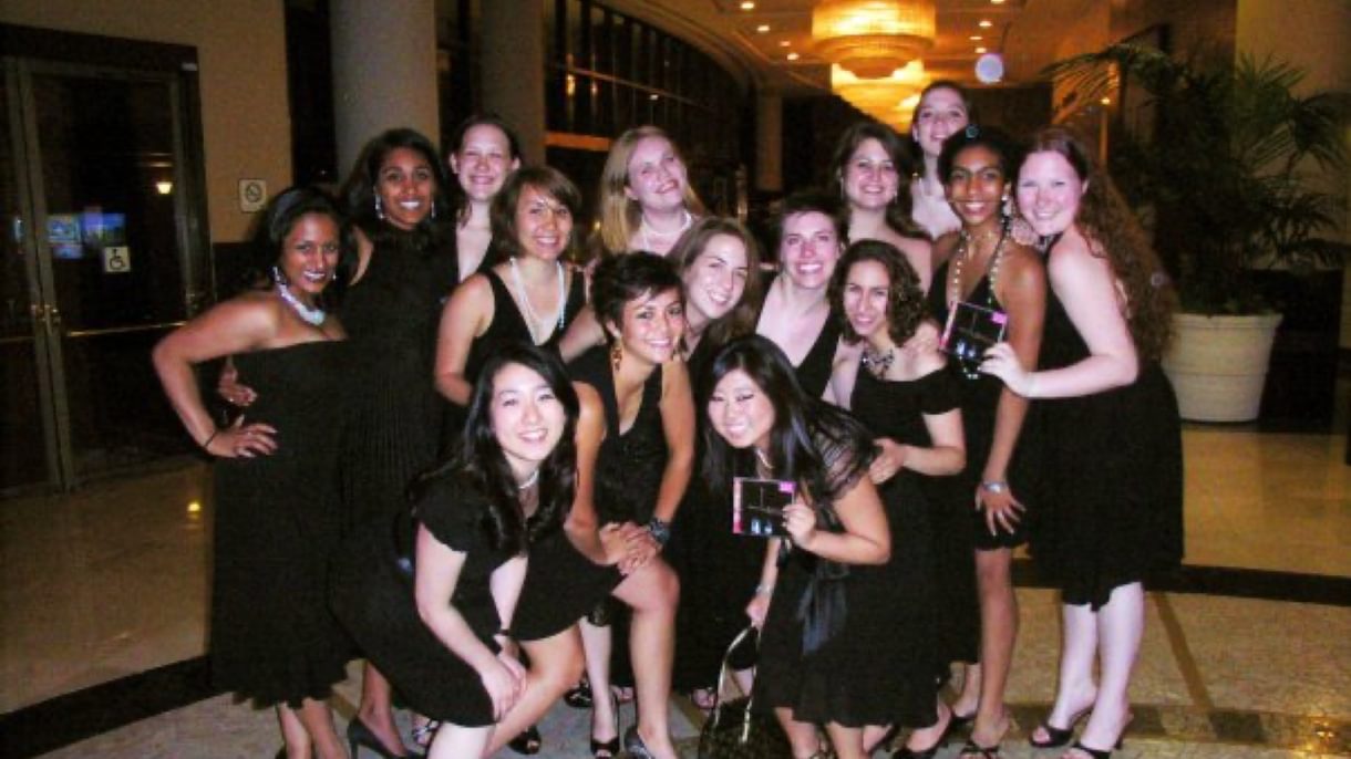Students in black dresses pose while holding CD cases