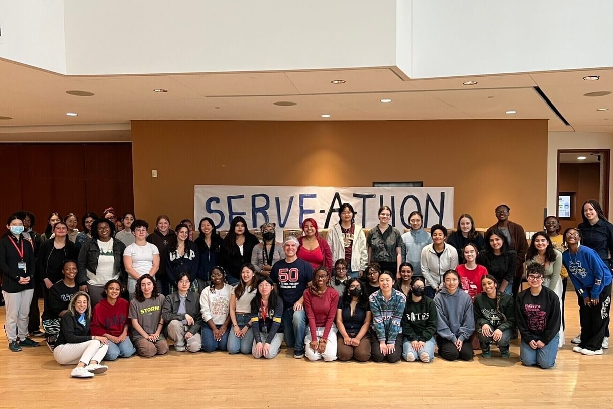 Large group photo with a serve-a-thon banner in the background