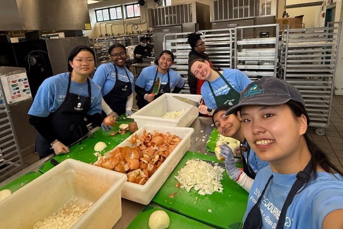 Students wearing aprons prep food in a commercial kitchen