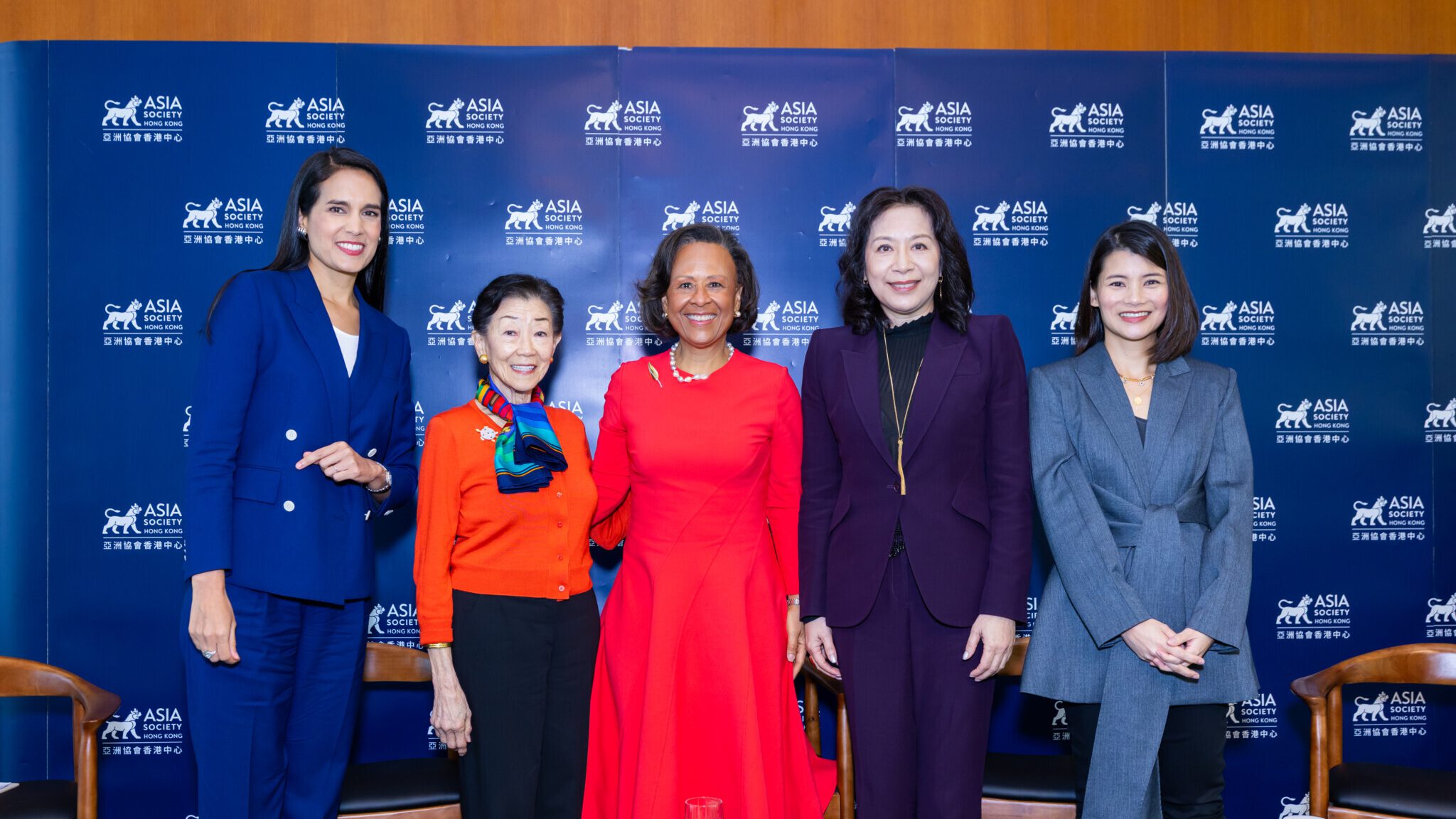 Panelists pose in front of the Asia Society backdrop
