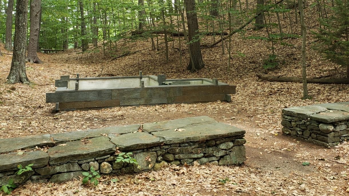 Low rock wall and the remnants of the foundation of a small building in the middle of the forest