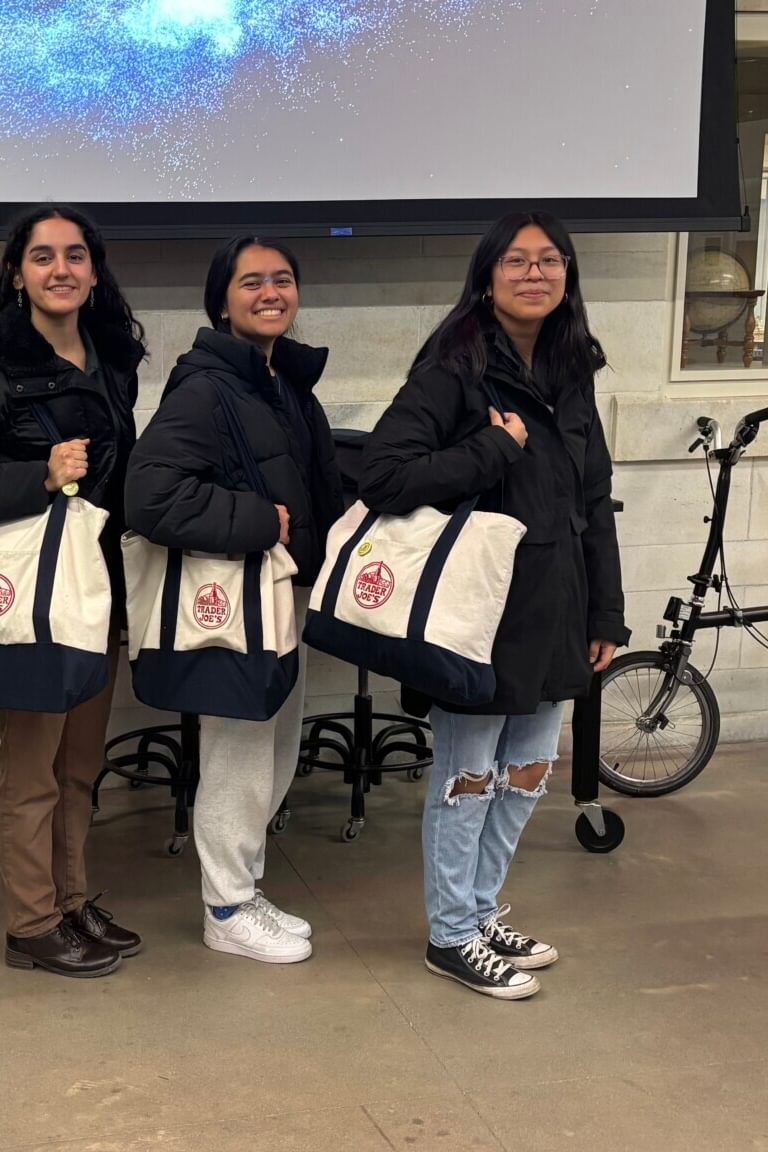 A professor and four students pose with Trader Joe's tote bags