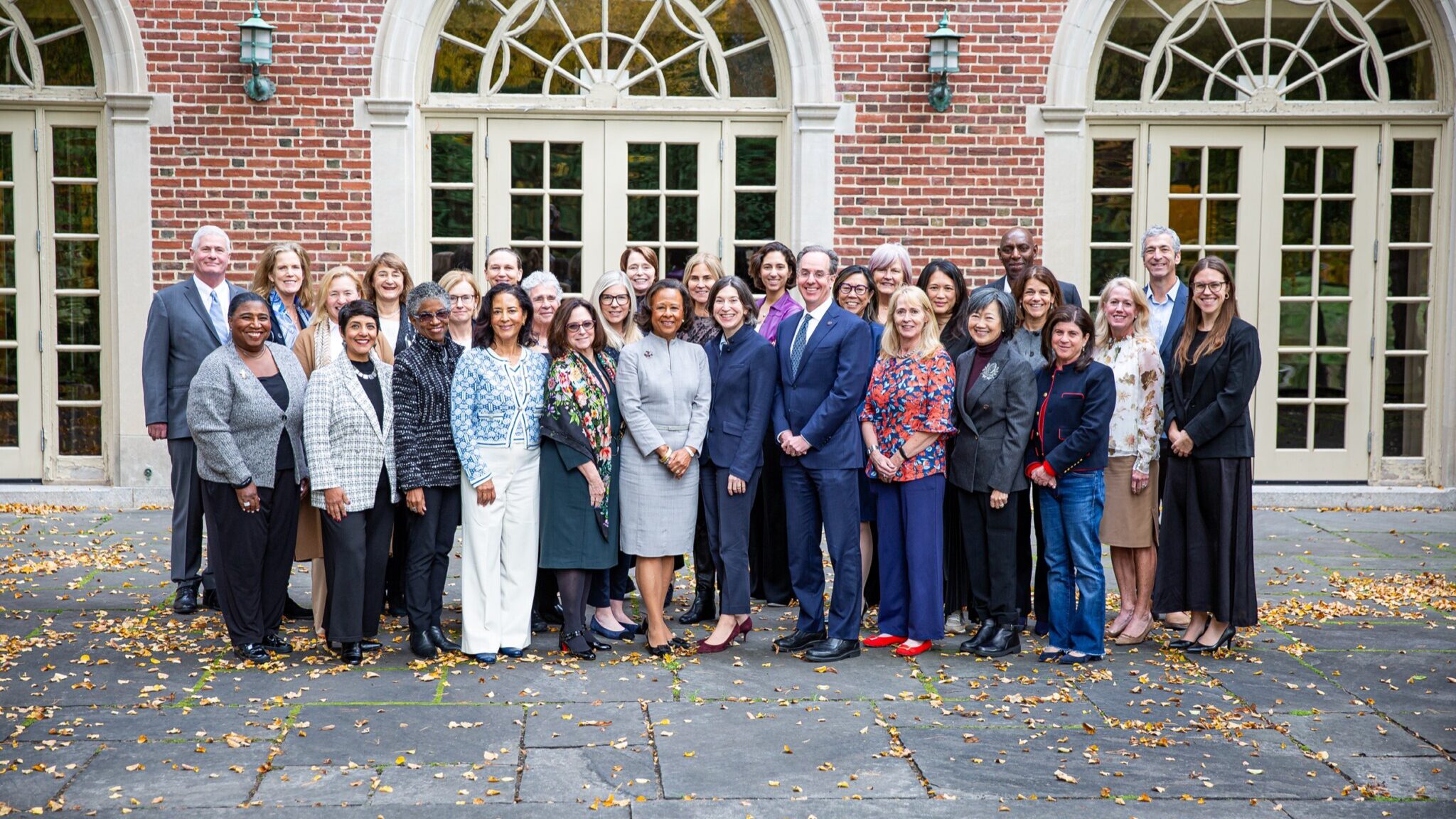 The board of trustees assembled in front of Alumnae Hall with fall leaves at their feet.