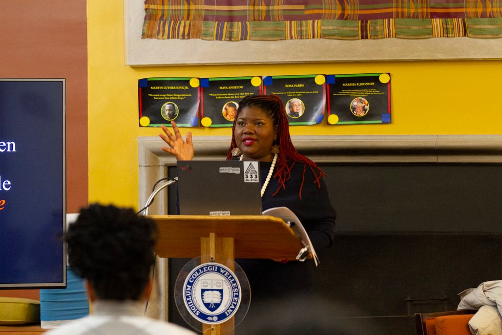 Professor Kellie Carter Jackson stands at a podium and speaks at a Harambee House event.
