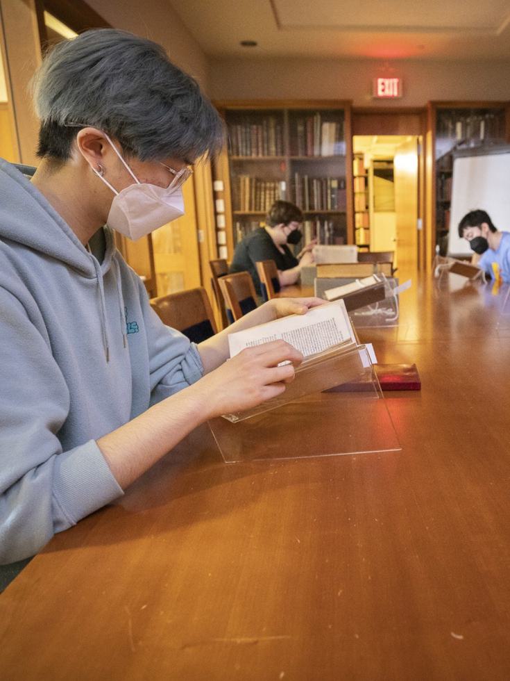 Students sit at a long wooden table examining rare books