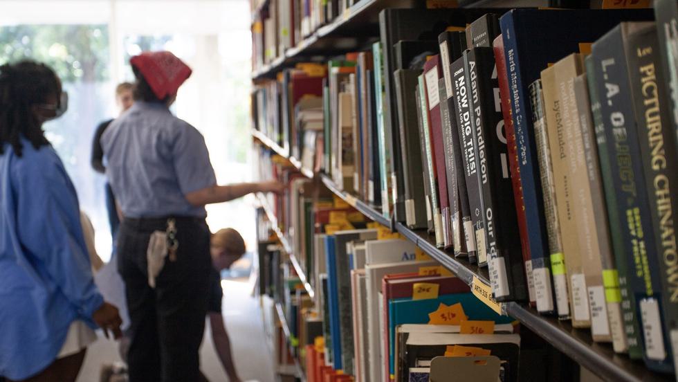 Students gathered in front of a tall bookshelf filled with books