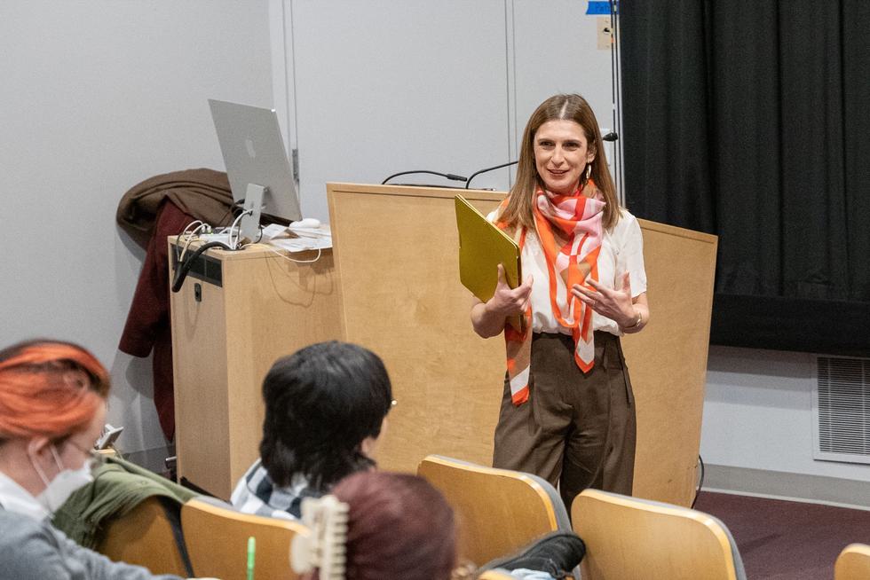Codruta Morari lectures to a group of students. She is holding a file folder.
