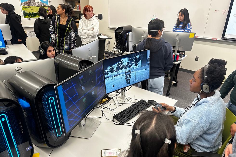 Students sit at computers and walk around in the playable media lab.