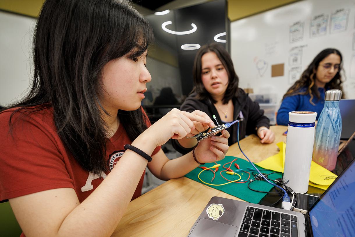Three students work with Arduino boards.