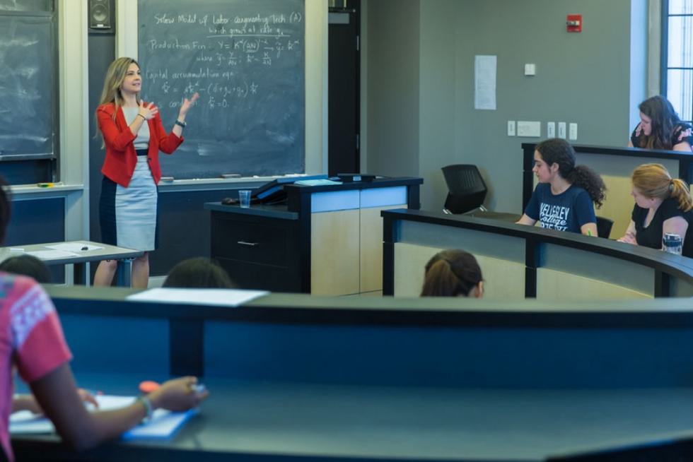 Olga Shurchkov stands in front of a blackboard and lectures to watching students.