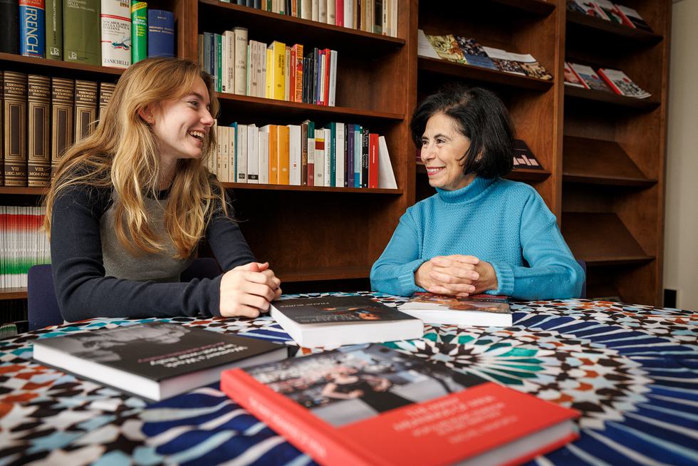 Professor Flavia Laviosa talks with a student as they sit at a table.