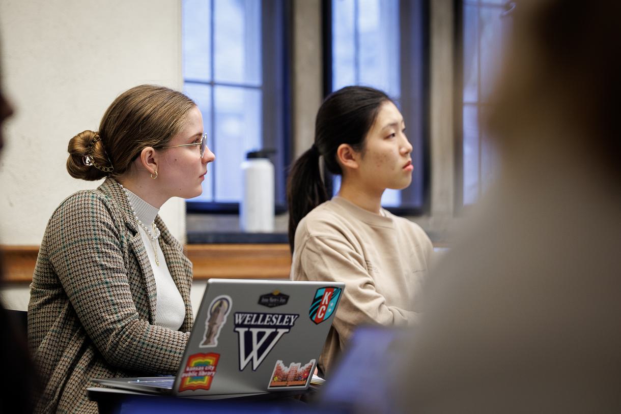 Two students at desks look intently off-frame