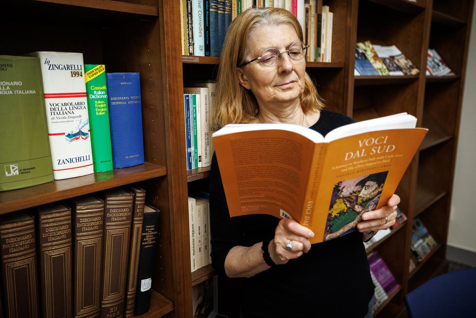 Daniela Bartalesi-Graf stands by a bookshelf and reads a book titled Voci dal sud