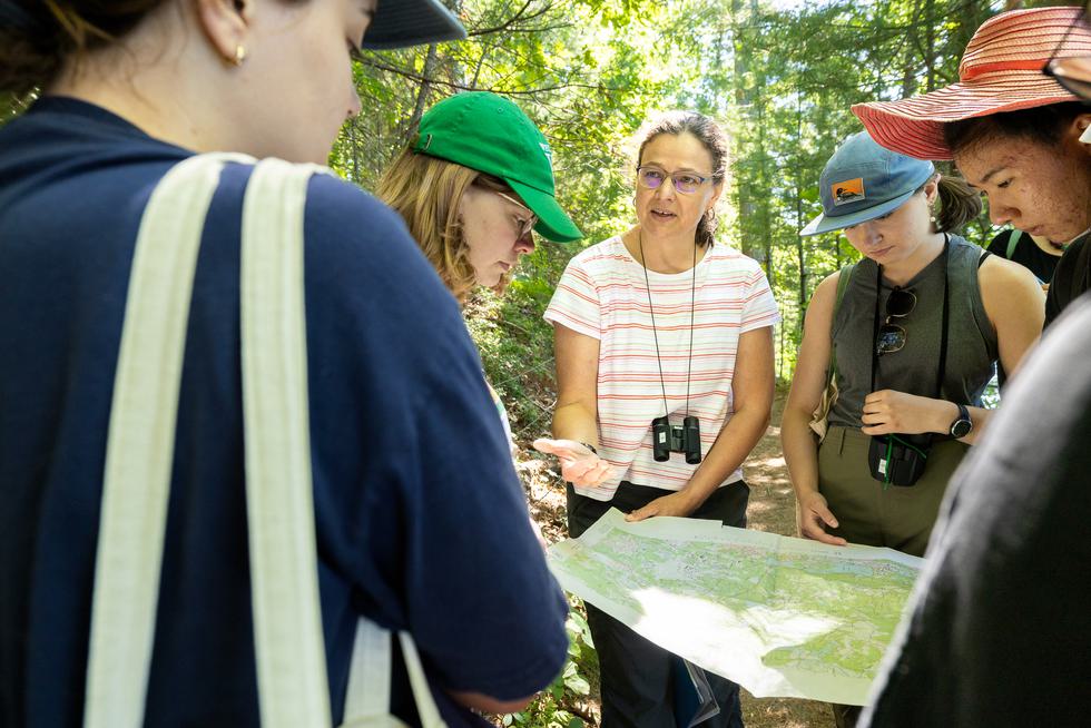 Gathered outside, a group of students look at a map and listen to an explanation from Katrin Monecke.