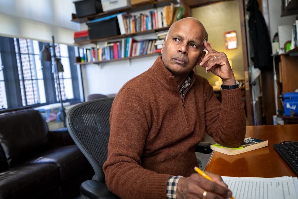 Nikhil Rao looks off camera thoughfully while sitting at his desk.