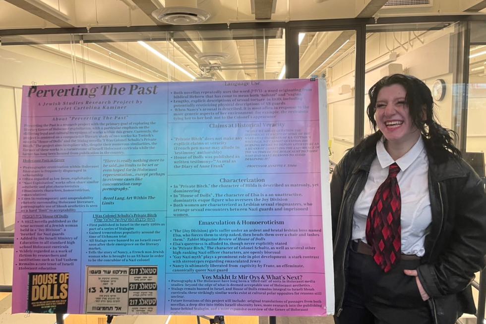 Ayelet Kaminer ’25 stands next to a poster and smiles.