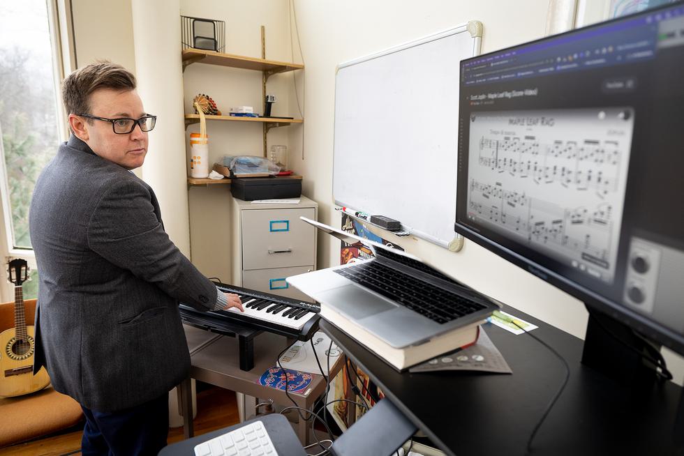 Professor Goldschmitt plays on their keyboard while reading notes off of a monitor.