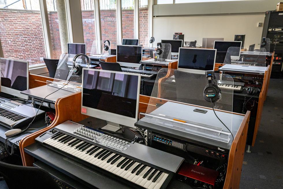 Rows of computer stations setup with headphones and piano keyboards.