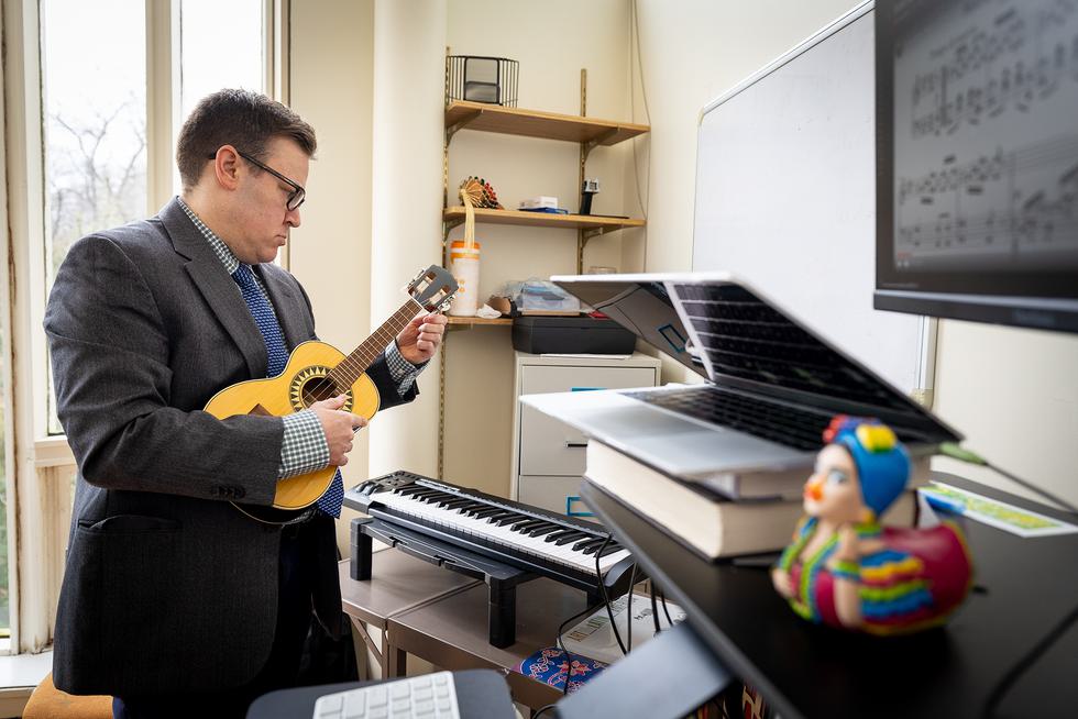 Kaleb Goldschmitt tunes a small guitar in his office.