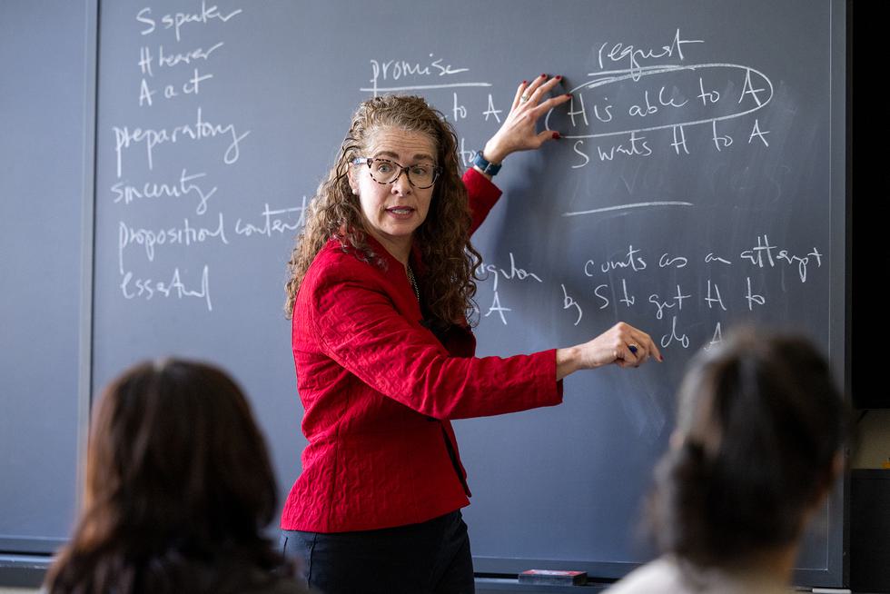 Professor Mary Kate McGowan points to statements written on the chalkboard.