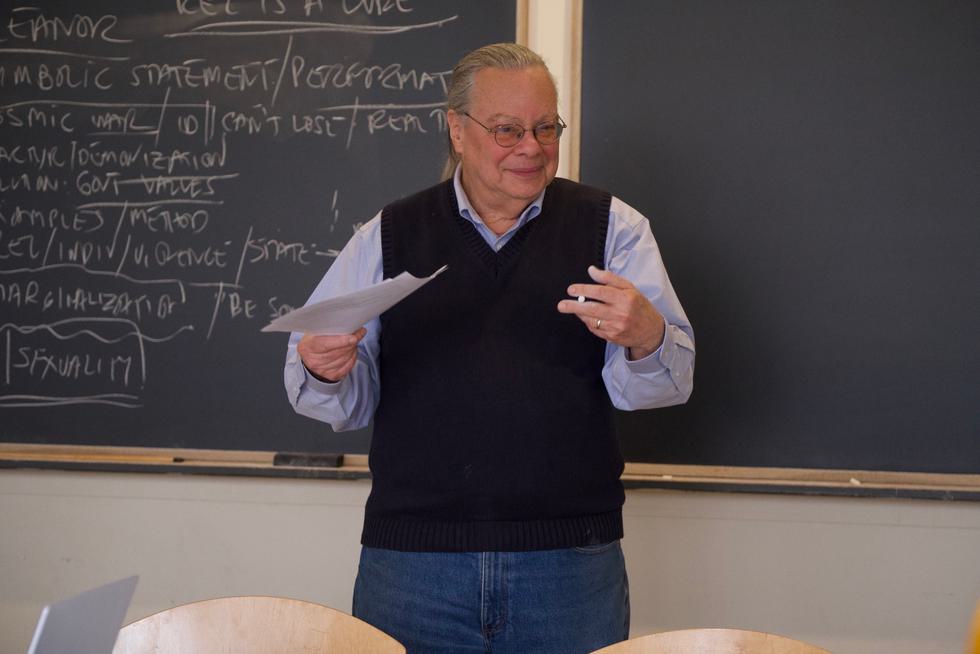 Stephen Marini stands at a chalkboard and lectures.