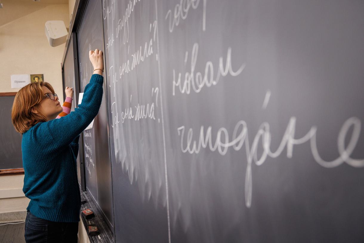 Student writing Russian on a chalkboard.