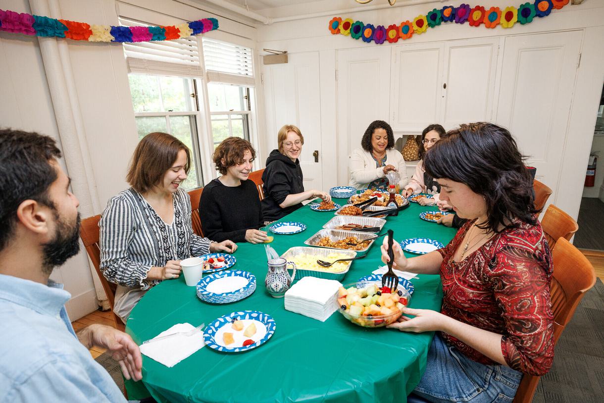 Students and faculty seated at a table sharing a meal