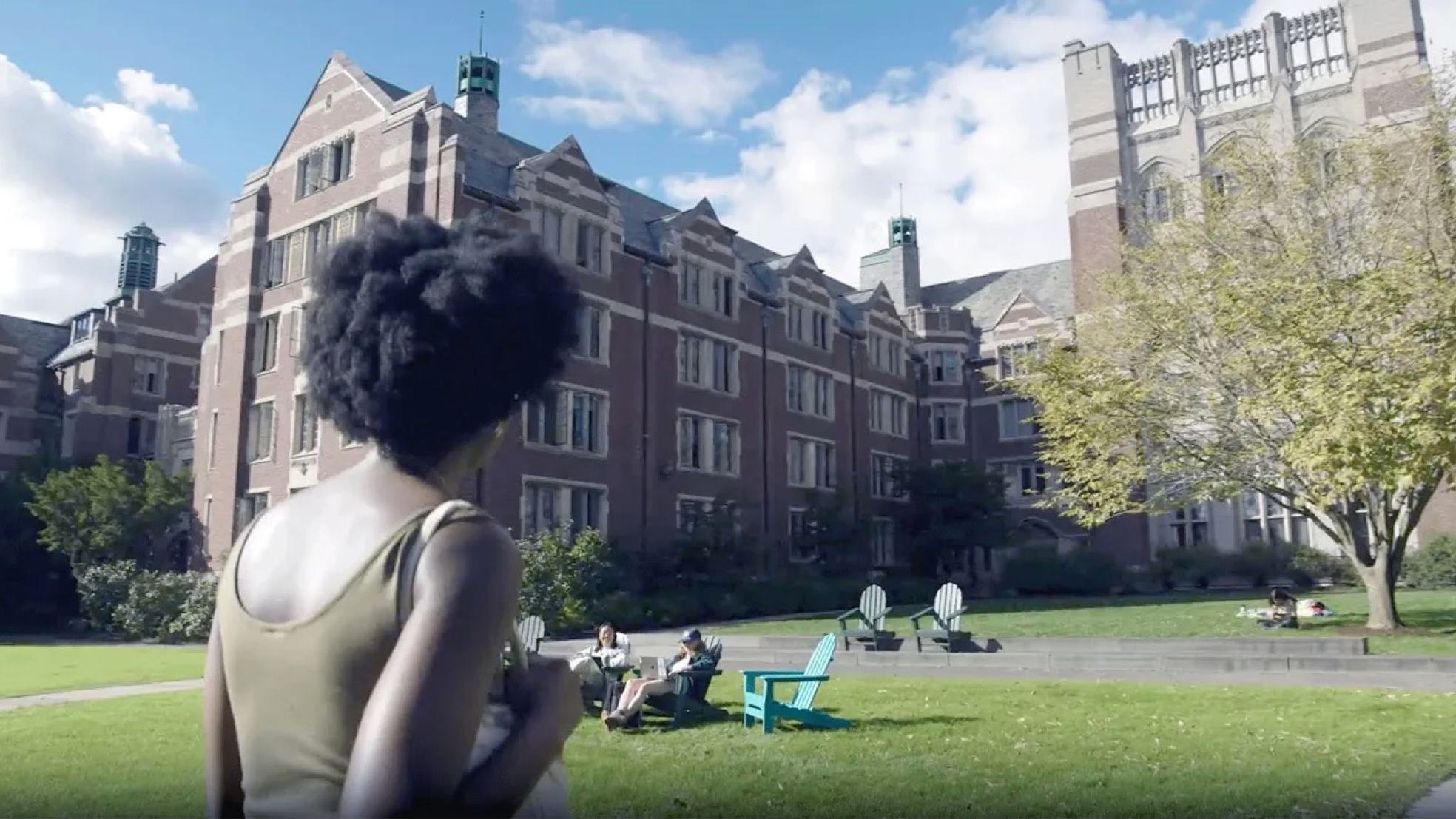 Student with back to camera facing Tower Court on a sunny spring day