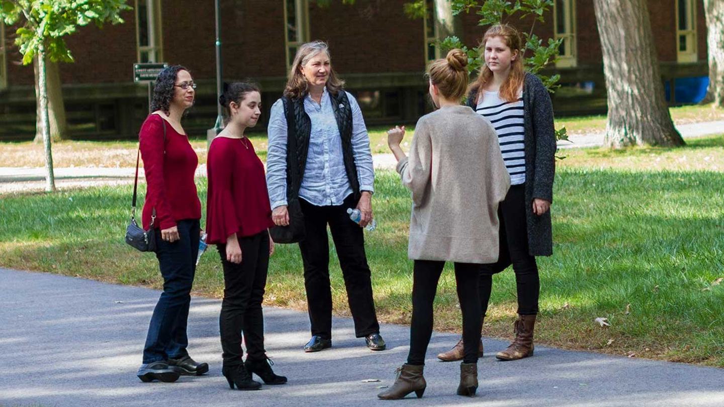 A group of women have a discussion in a circle on campus.
