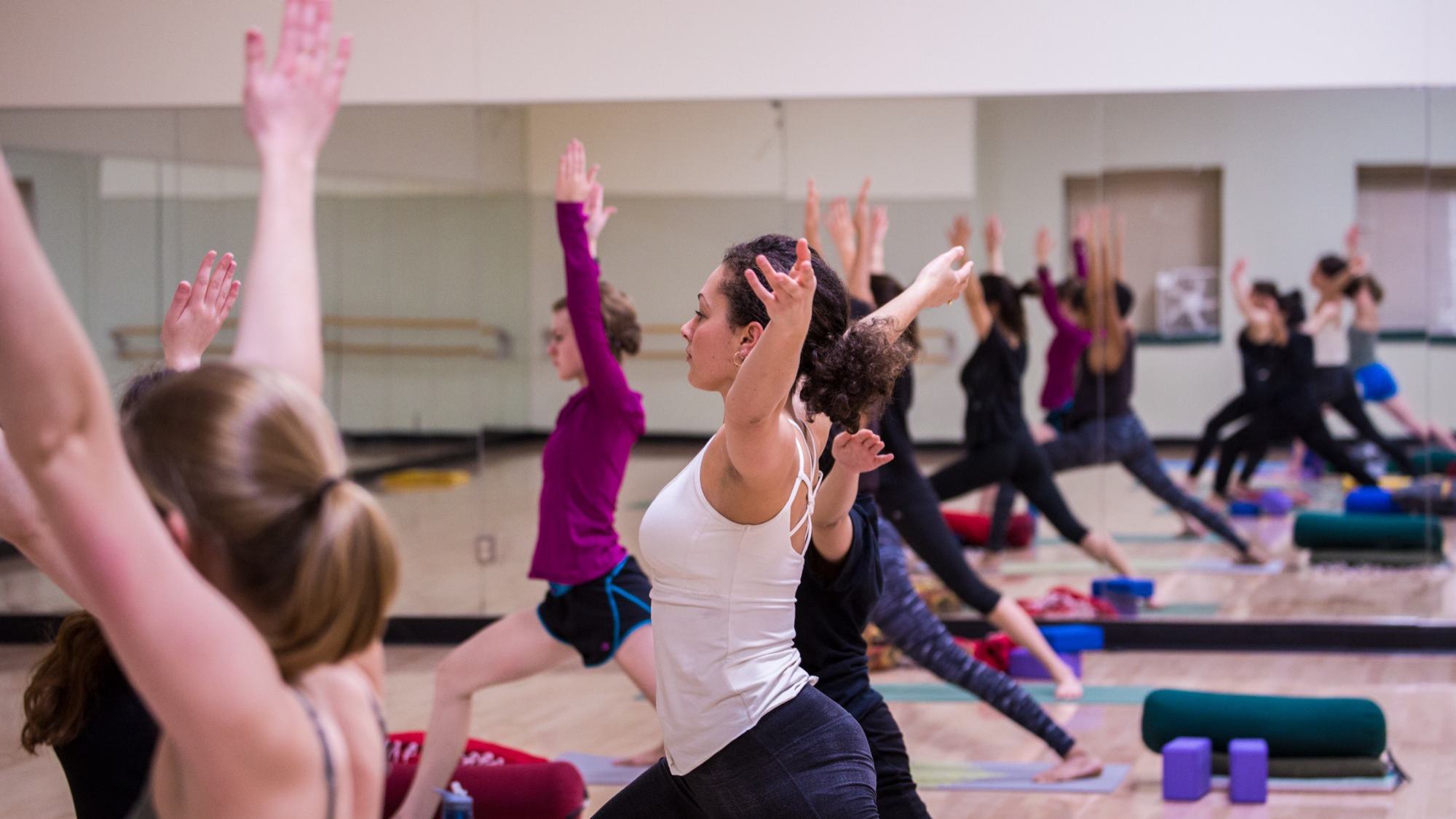 Group of students doing a yoga pose next to a mirror.