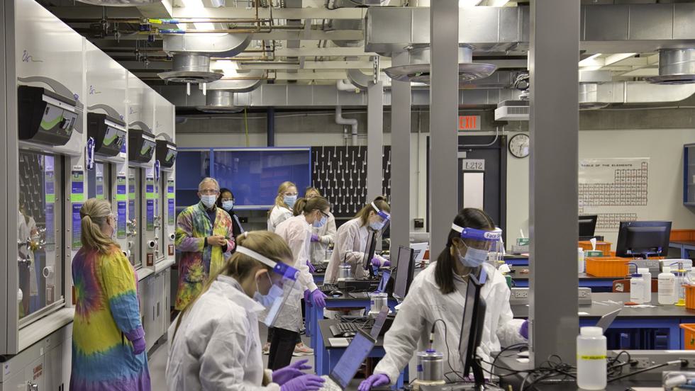 Students wearing lab coats take measurements off instrumentation in the chemistry lab