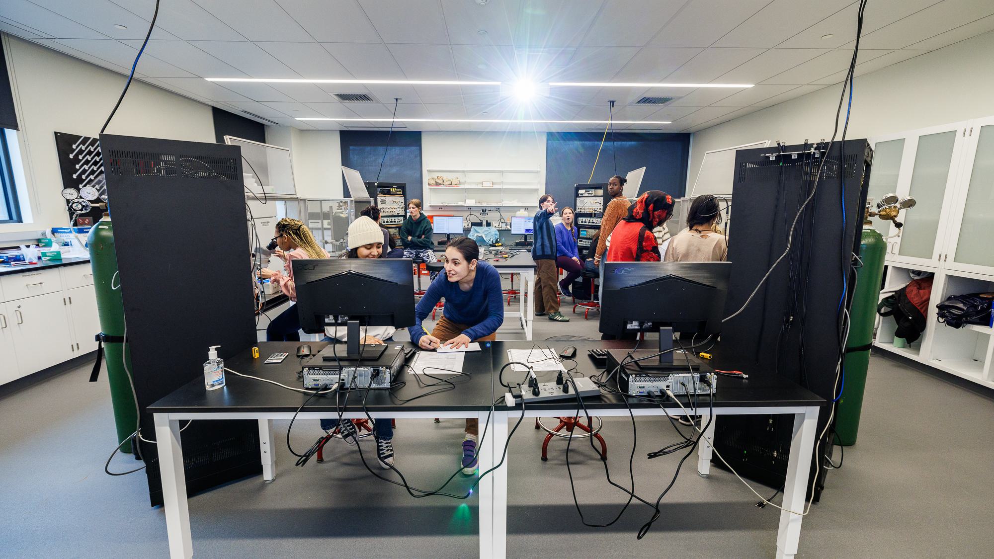Students work among computers, microscopes, and other equipment in the Electrophysiology Lab