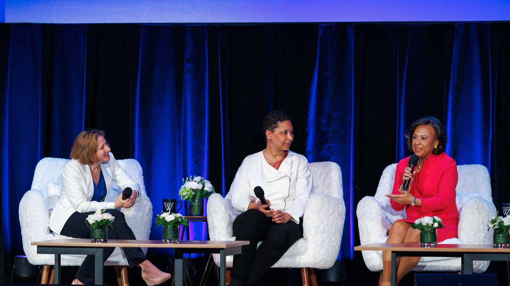 Stacie Goddard, Danielle Allen, and Paula Johnson participant in panel discussion on stage at the summit.