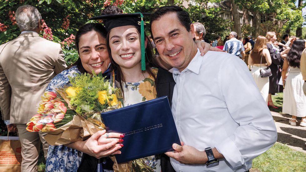 A student holds a Wellesley diploma and embraces loved ones