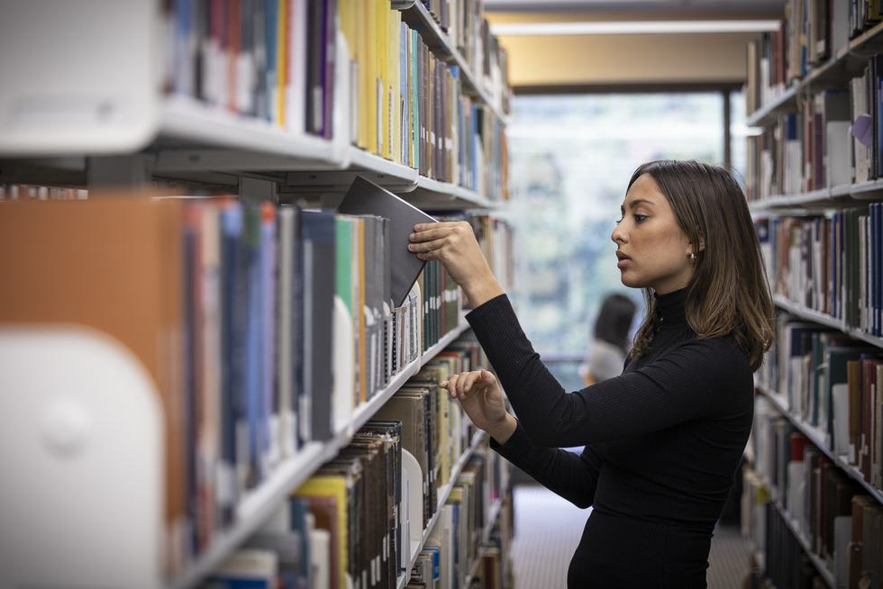 Student pulling a book off a shelf