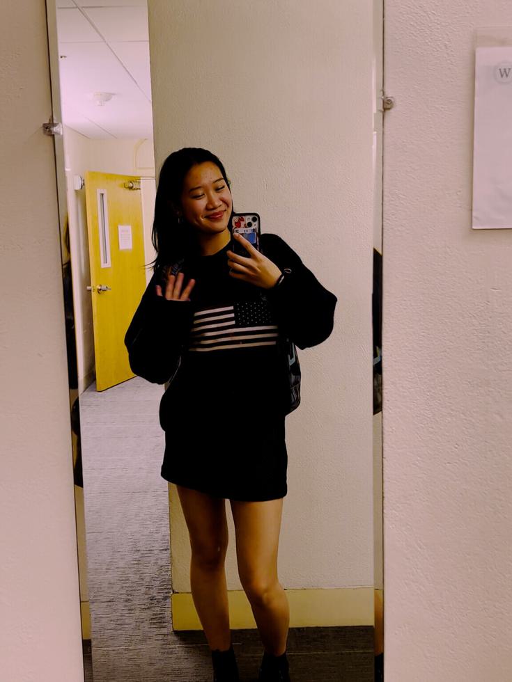 Monica Xu waving and taking a selfie in front of a mirror