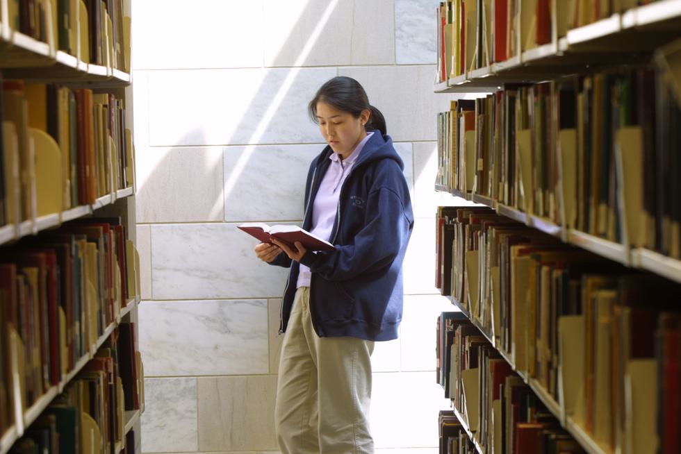 Student searching for library materials in the book stacks