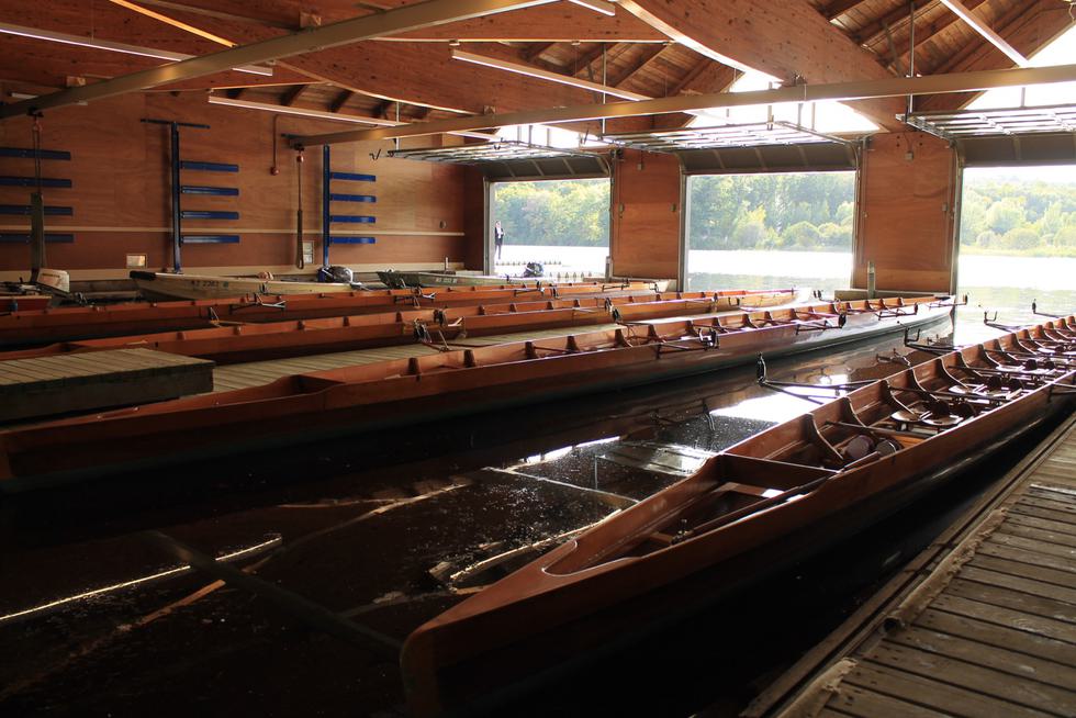 Four crew shells sit parked inside a boathouse.