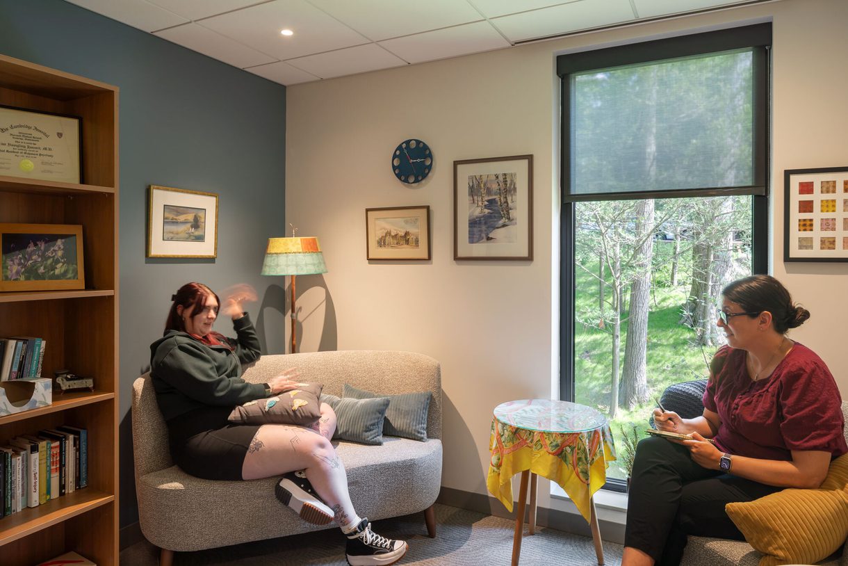 Two students chat in comfortable chairs in a colorfully decorated room