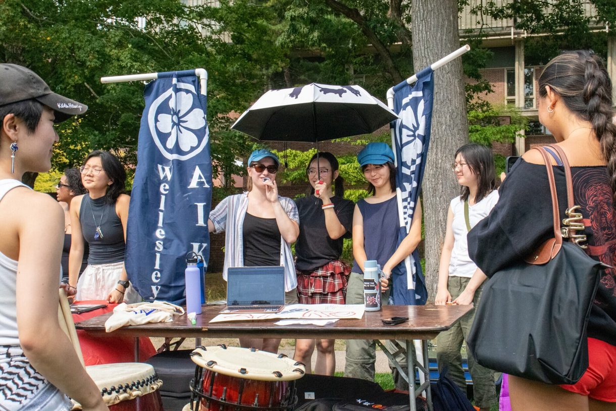 Students representing Wellesley Aiko stand with banners and drums at a table at the annual Student Organization Fair
