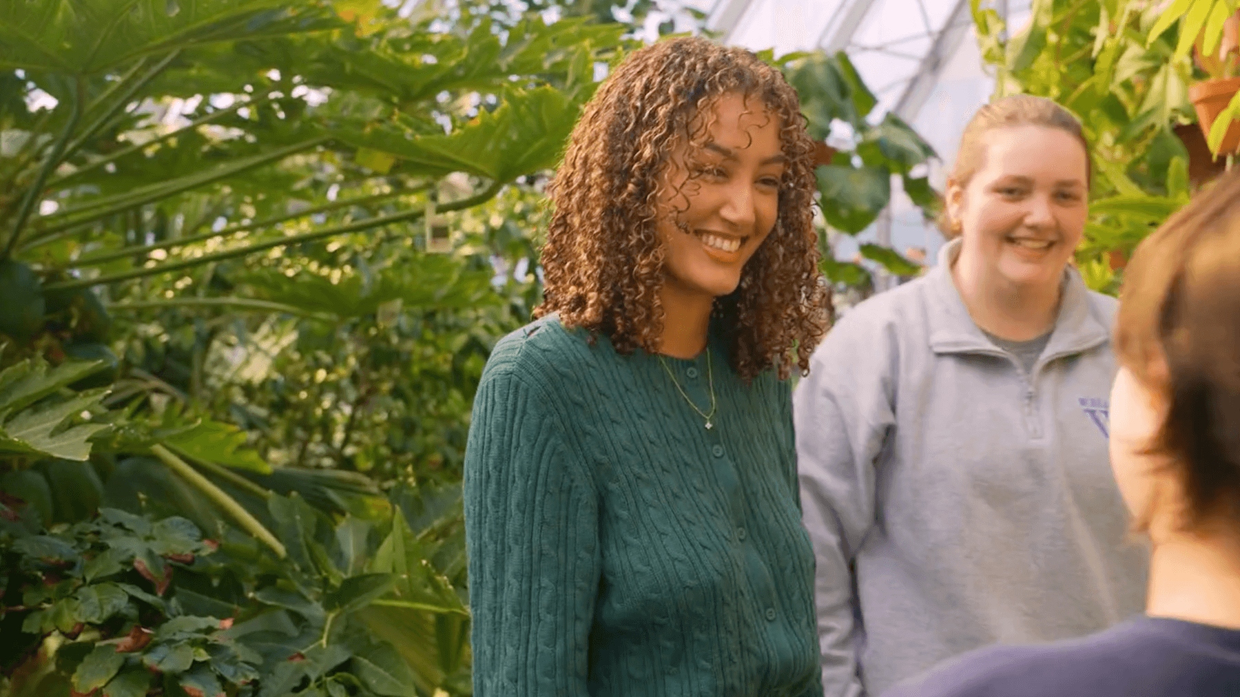 Still image from video with three students in the Global Flora conservatory.