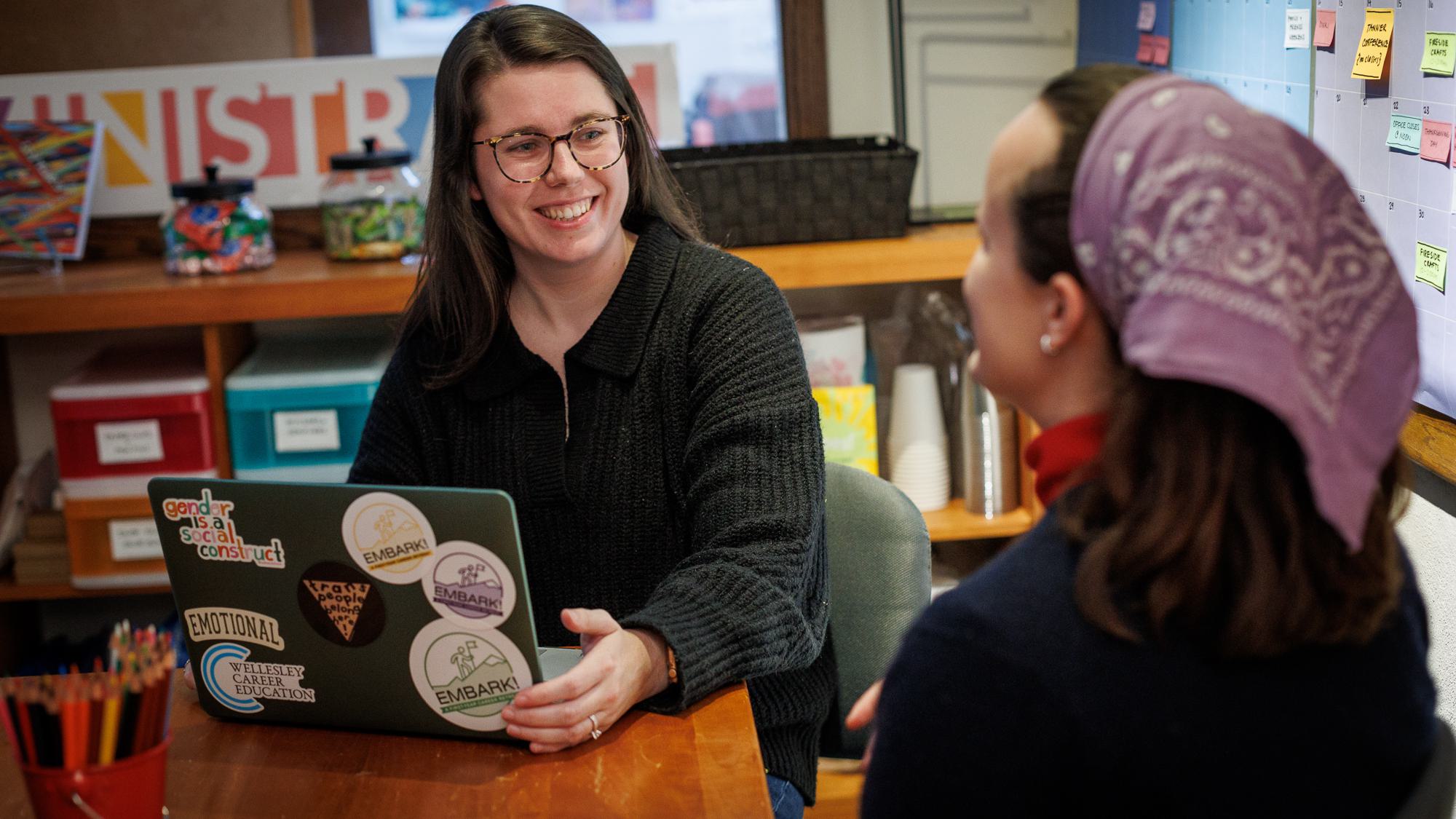 Two students at table with laptop.
